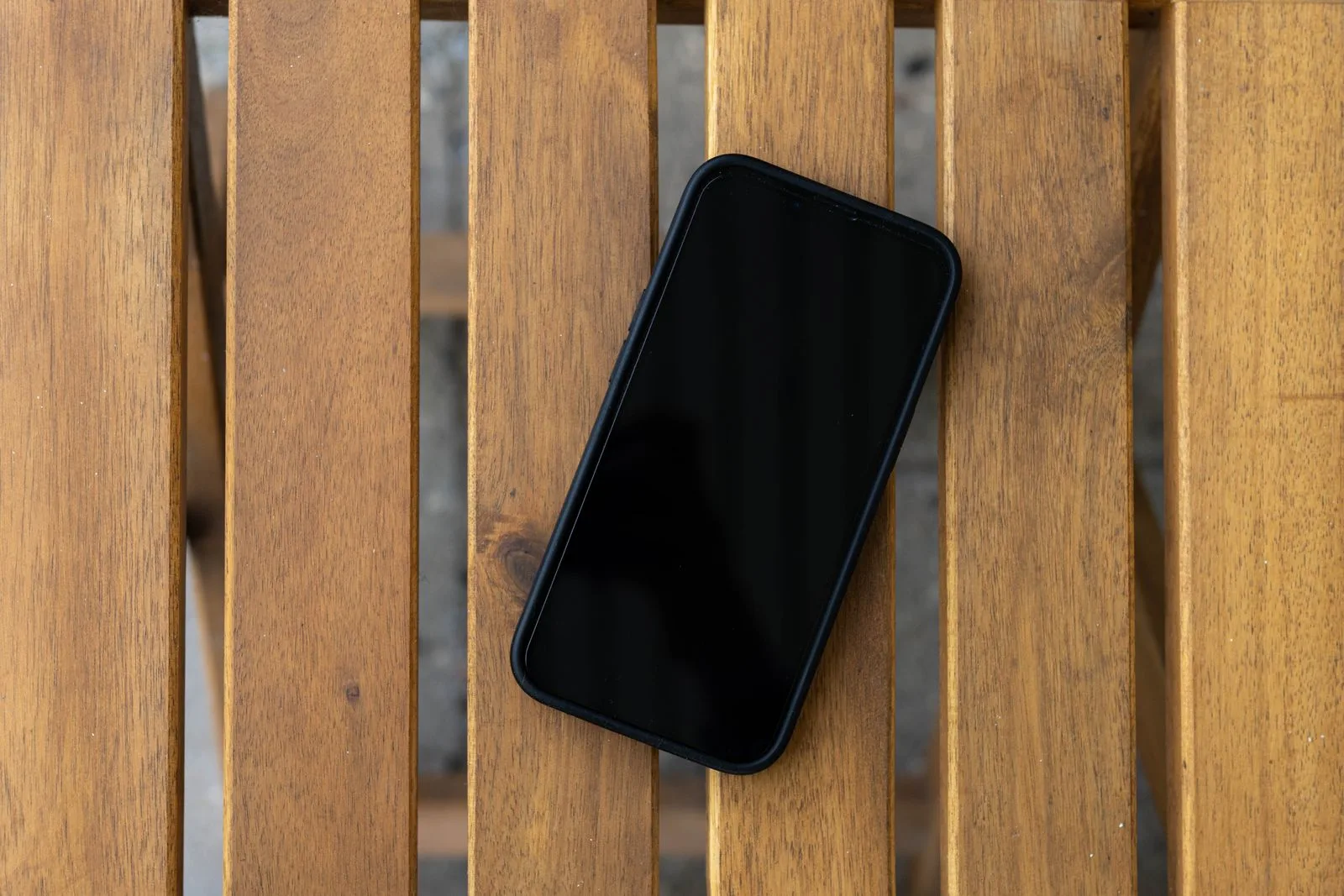 Uno smartphone con lo schermo nero su un tavolo a listelli di legno